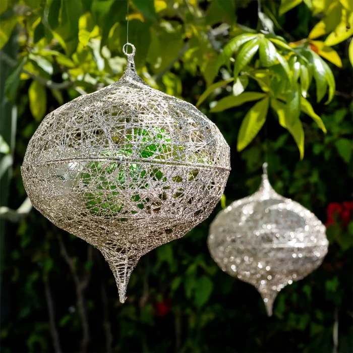 Decorative hanging lanterns with intricate designs against a green leafy background