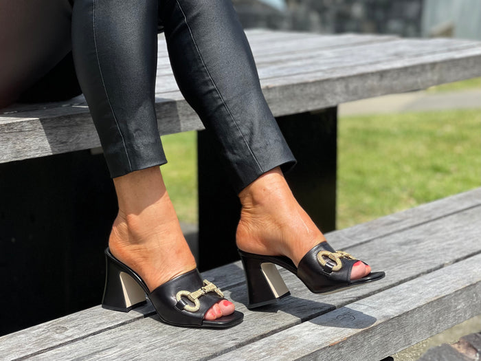 Classy European women's sandals with gold bit detail. Mule style on chunky block heel. Wedding or special occasion slide. In black.