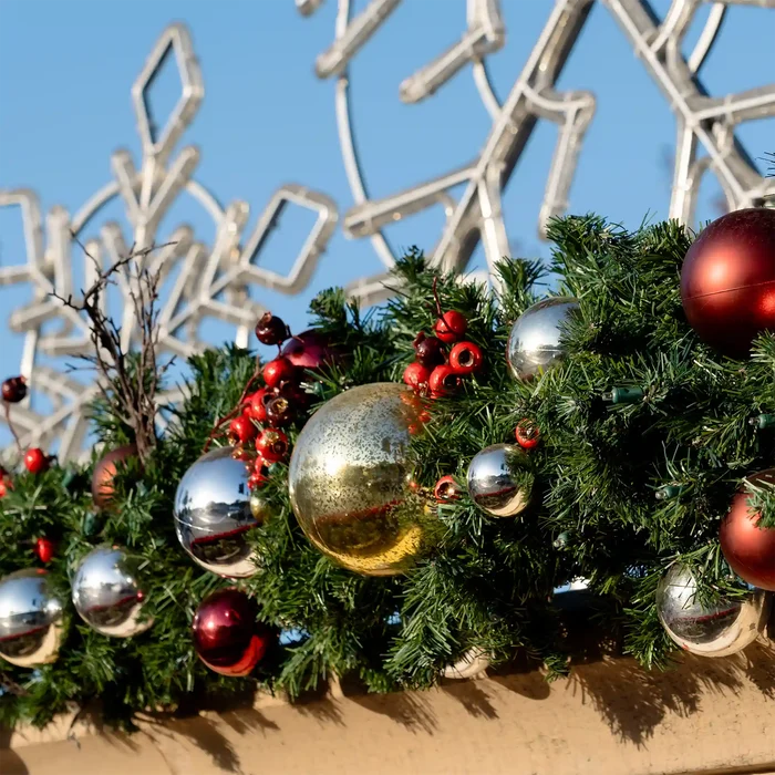 Decorative Christmas wreath with colorful ornaments against a modern architectural background