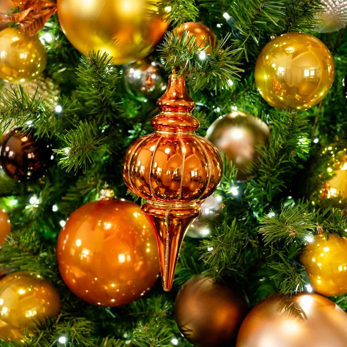 A metallic bronze Christmas tree topper ornament hanging among green pine branches and surrounded by shiny gold and bronze baubles with small white lights.